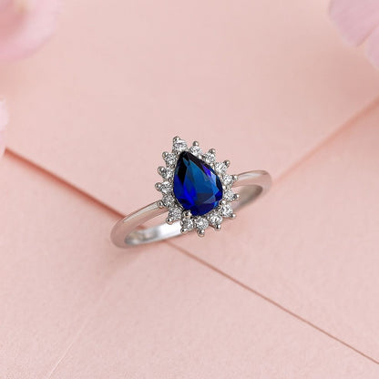 Silver ring with a blue gemstone on a pink background