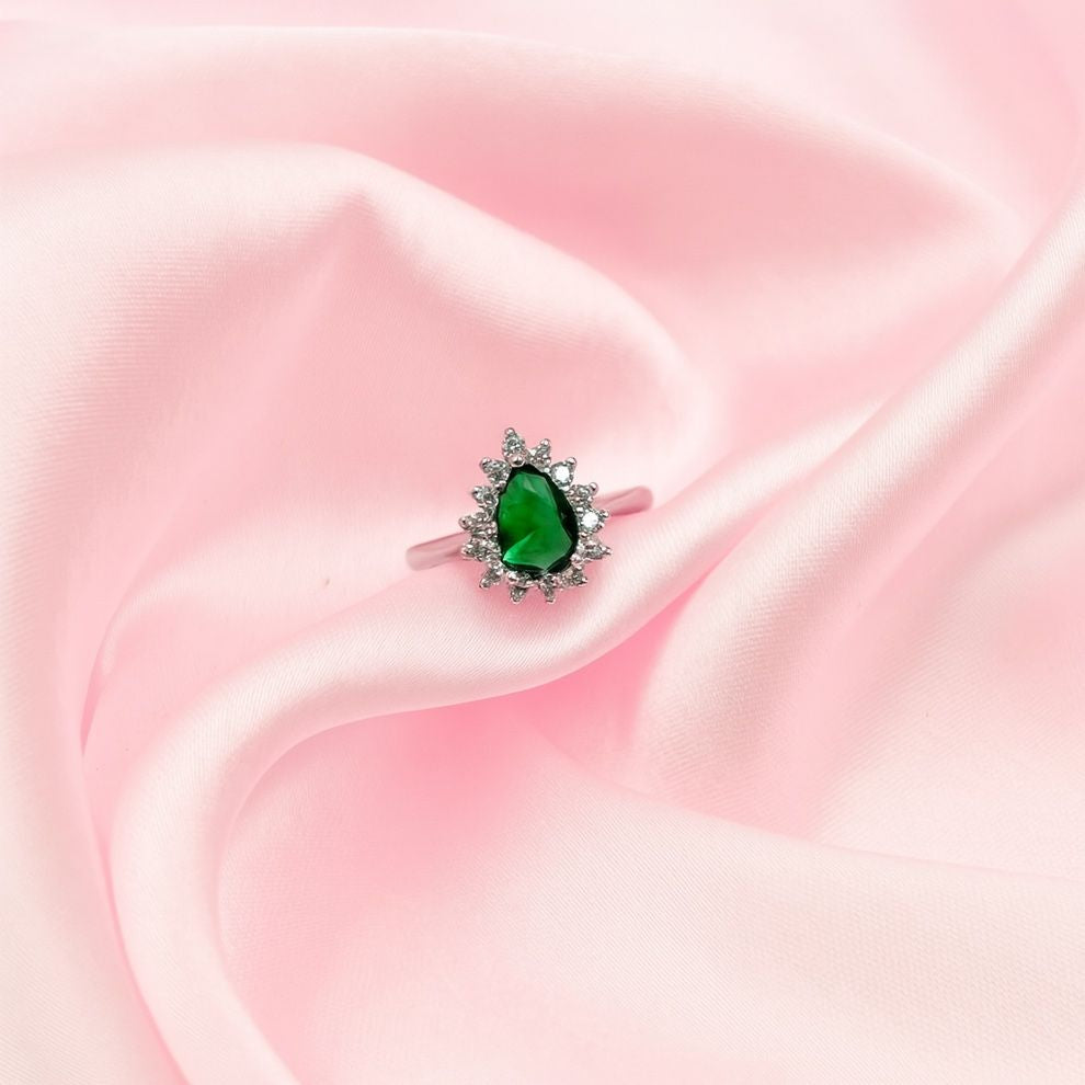 Ring with a green gemstone on a pink fabric background