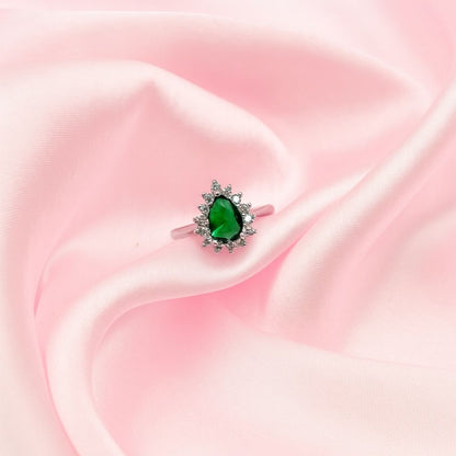 Ring with a green gemstone on a pink fabric background