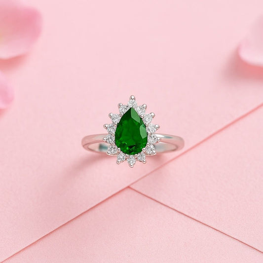 Silver ring with a green gemstone on a pink fabric background