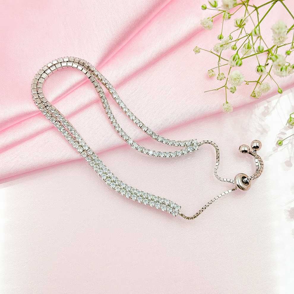 Silver necklace with clear stones on a pink background