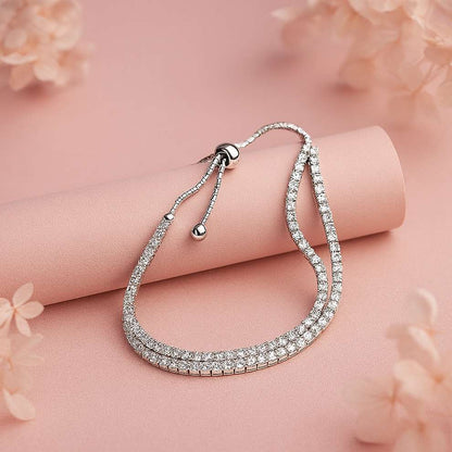 Silver bracelet with clear stones on a pink surface with floral elements