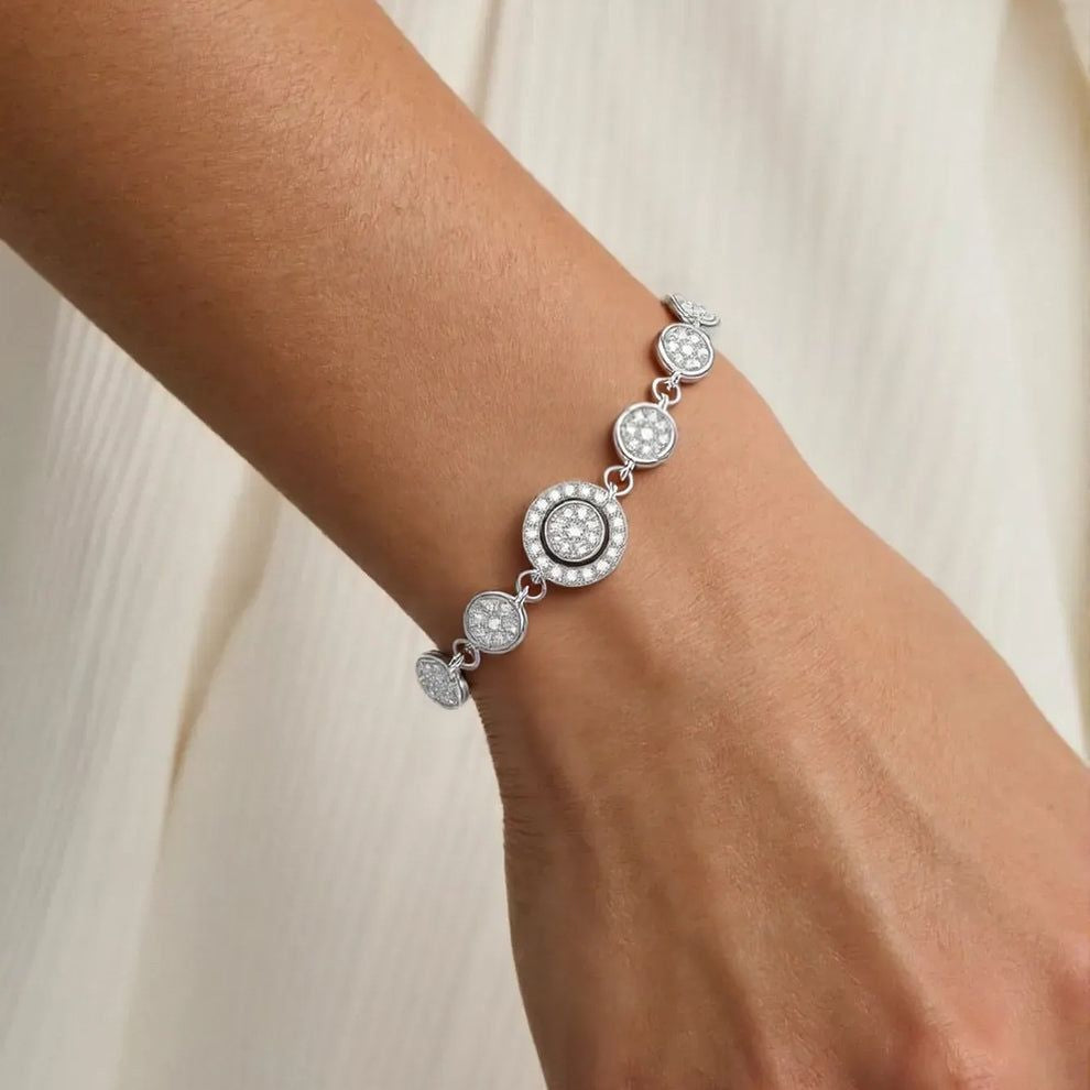 Silver bracelet with circular beads on a wrist against a neutral background