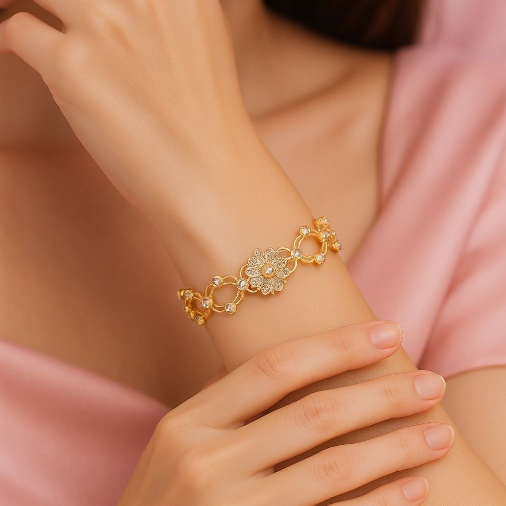 Gold bracelet with floral design on a wrist and a soft pink dress
