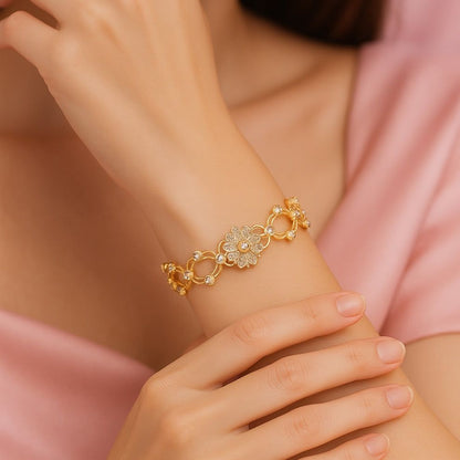 Gold bracelet with floral design on a wrist and a soft pink dress