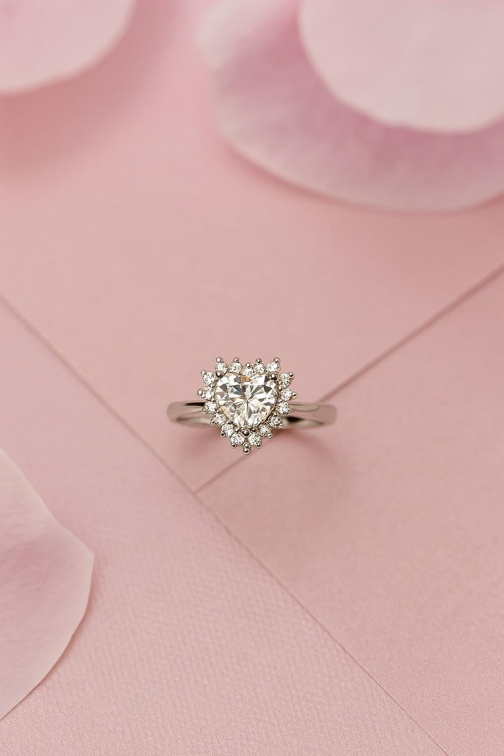 Heart-shaped white stone silver ring on a pink fabric background
