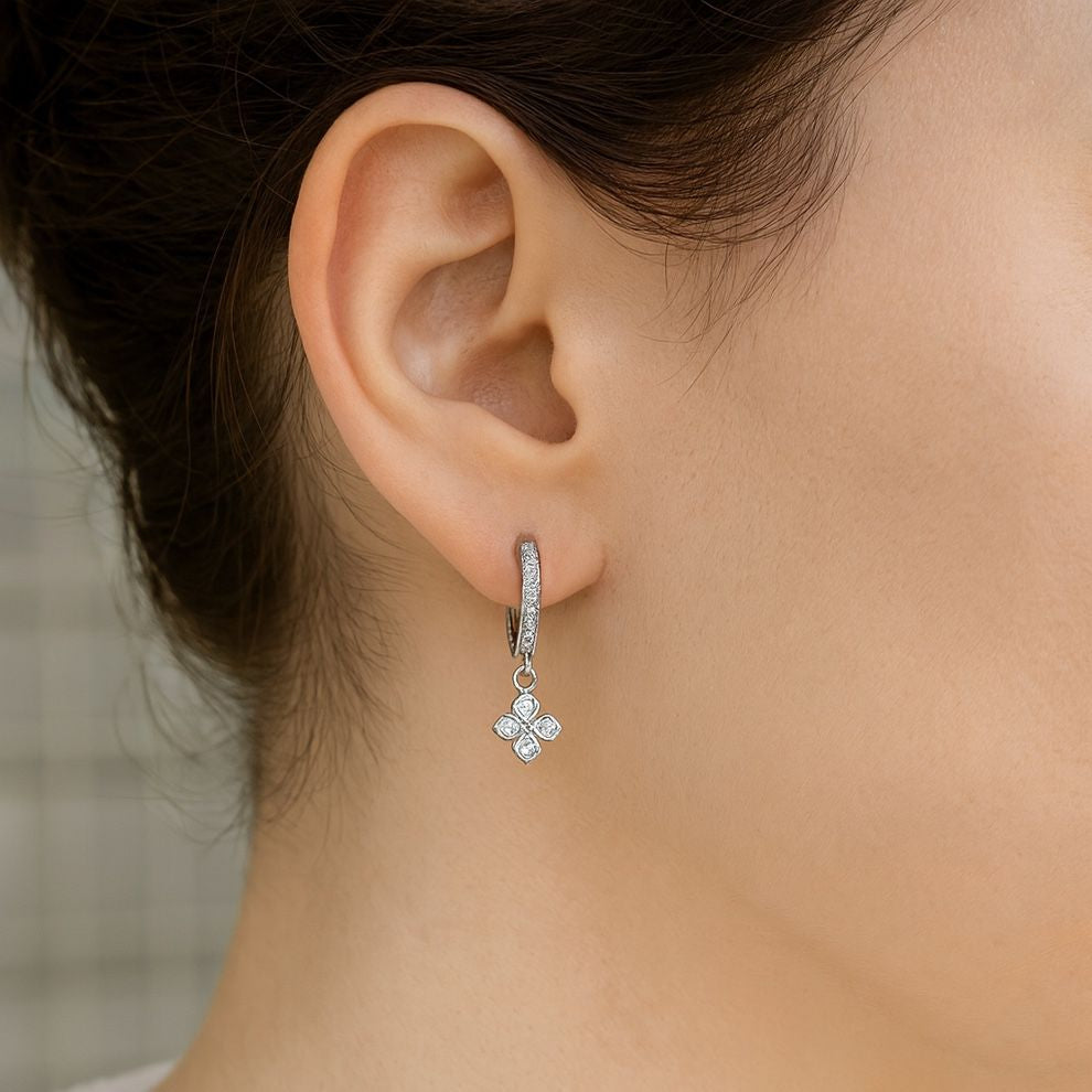 Close-up of an ear wearing a silver earring with floral design.