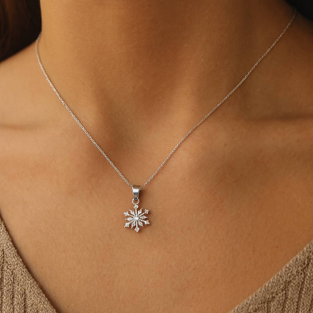 Silver necklace with a snowflake pendant on a person wearing a beige top.